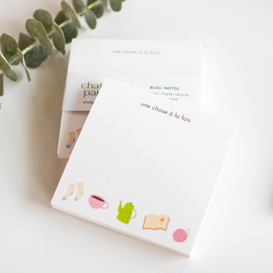 A stack of notepads and a eucalyptus branch.